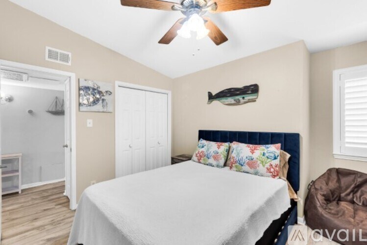 A bedroom with a bed, a ceiling fan, and a wall-mounted fish decoration.