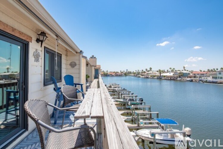 A wooden deck with chairs and a table overlooks a body of water.