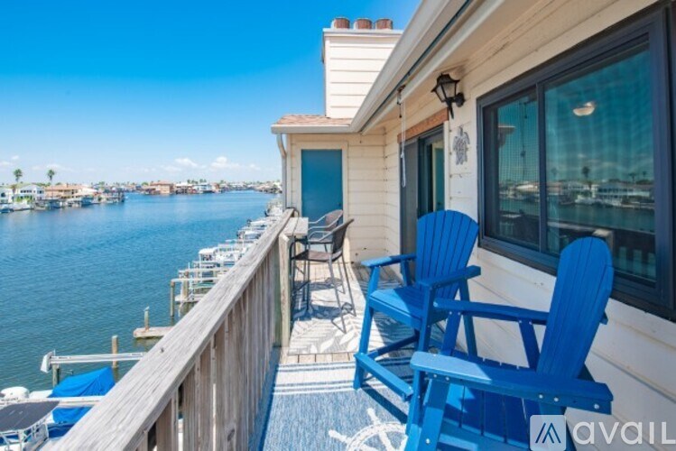A blue chair is on a balcony overlooking a body of water.