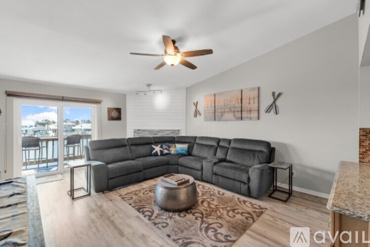 A living room with a grey sofa and a ceiling fan.