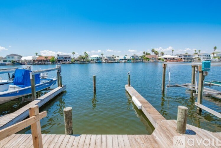 A wooden dock extends into a calm body of water with boats docked at the other end.