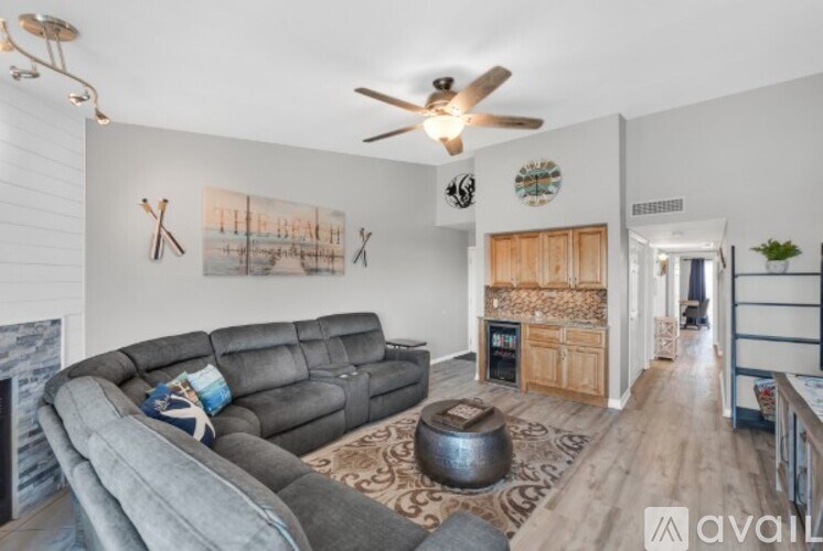 A living room with a grey couch and a painting of a beach scene on the wall.