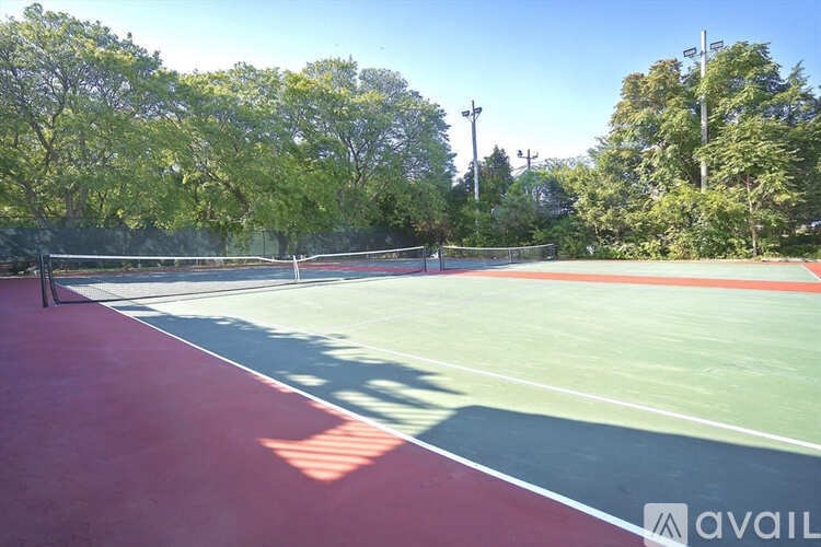 A tennis court with a red surface and green boundary lines.