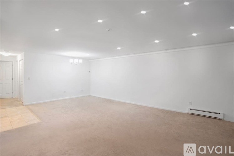 A spacious room with a carpeted floor and a wall-mounted air conditioner unit.