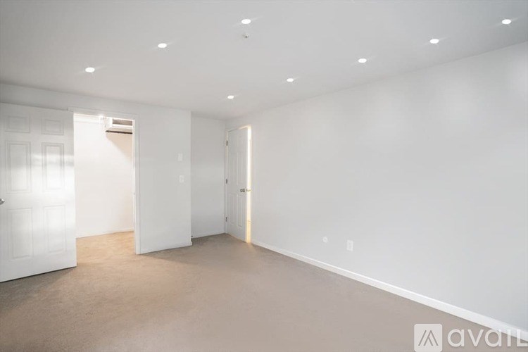 A large empty room with white walls and carpeted floor.