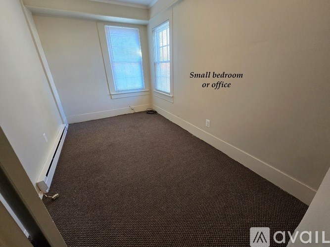 A small bedroom or office with a carpeted floor and a window.