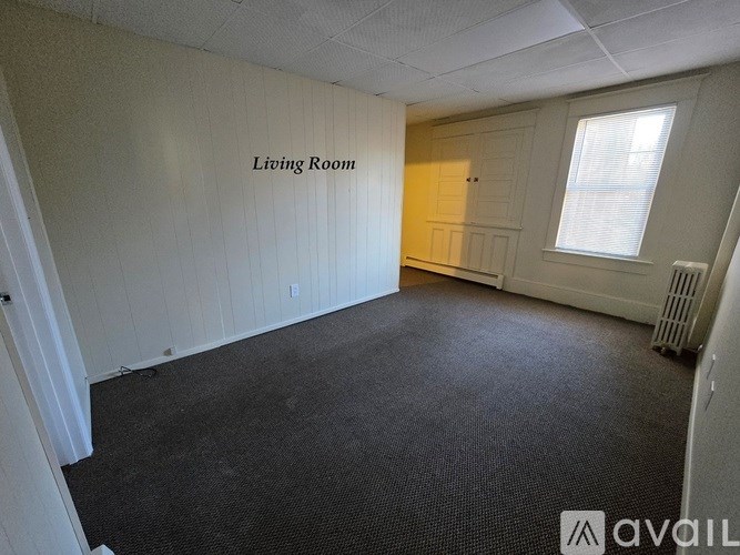 A living room with a carpeted floor and a window.