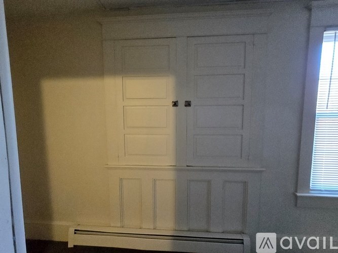 A white wooden cupboard with a radiator beneath it.