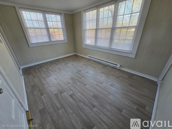A room with wooden flooring and two windows.