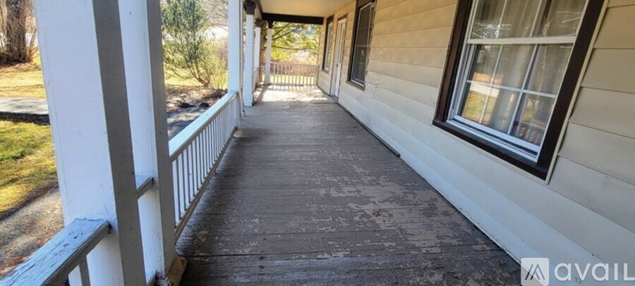 A porch with a white railing and a black floor.