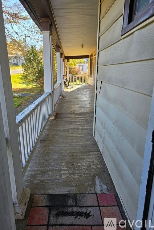 A porch with a red and black mat on the floor.