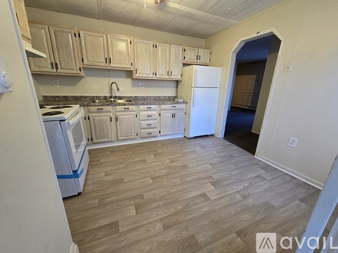 A kitchen with wooden floors and white appliances.