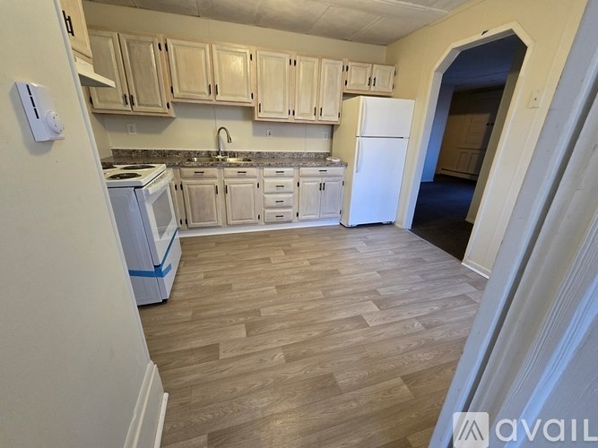 A kitchen with wooden floors and white appliances.