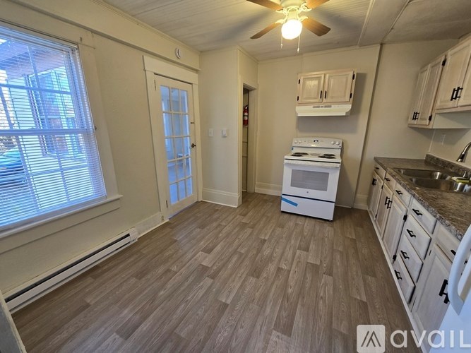 A kitchen with a white oven and wooden flooring.