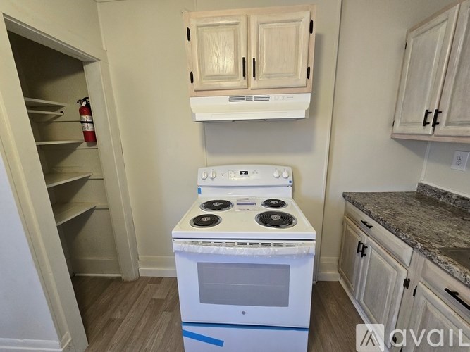 A white stove in a kitchen with wooden cabinets.