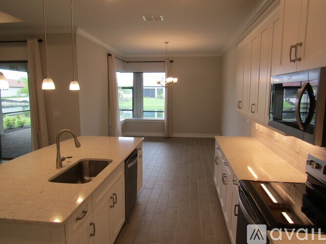 A kitchen with white cabinets and a large island with a sink.