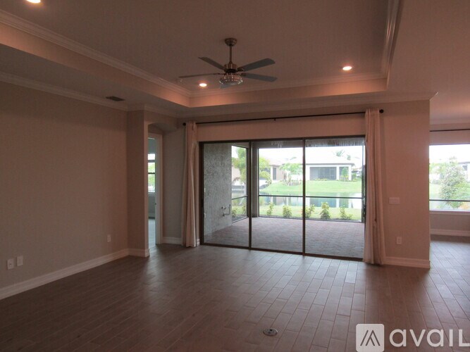 A spacious room with a ceiling fan and sliding glass doors leading to a patio.