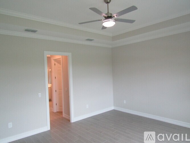 A room with a ceiling fan and a doorway leading to another room.