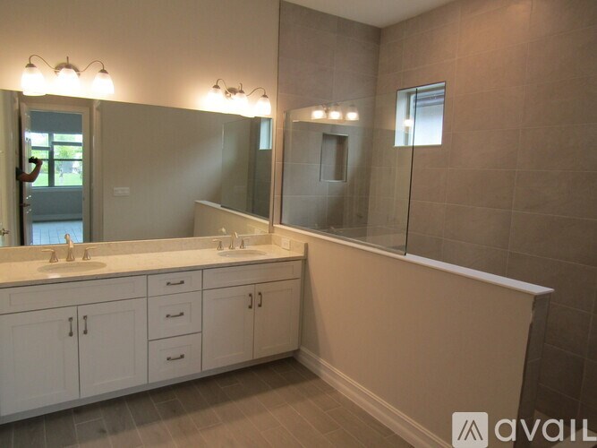 A bathroom with a large mirror and a vanity with two sinks.