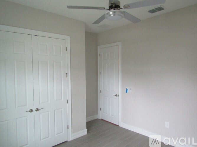 A room with a ceiling fan and two doors.