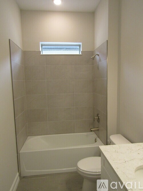 A bathroom with a toilet, tub and a window.