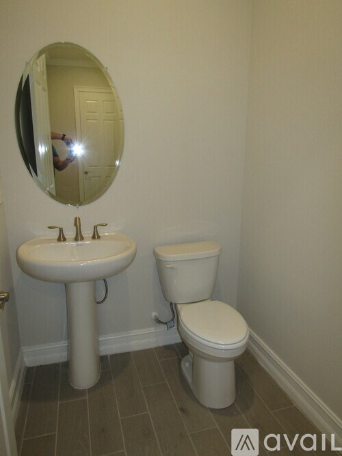 A bathroom with a sink, toilet and mirror.
