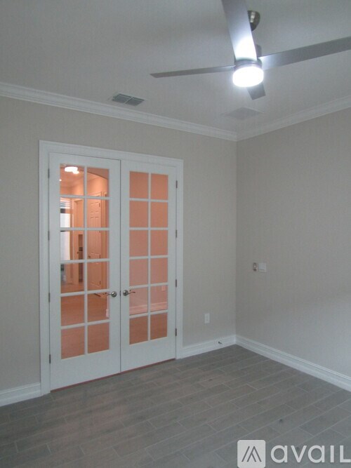 A room with a white door and a ceiling fan.