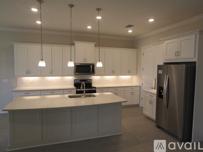 A kitchen with white cabinets and a stainless steel refrigerator.