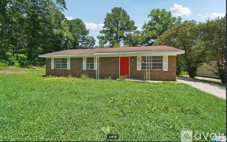 A small house with a red door is surrounded by greenery.