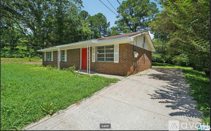 A house with a red door is surrounded by greenery.