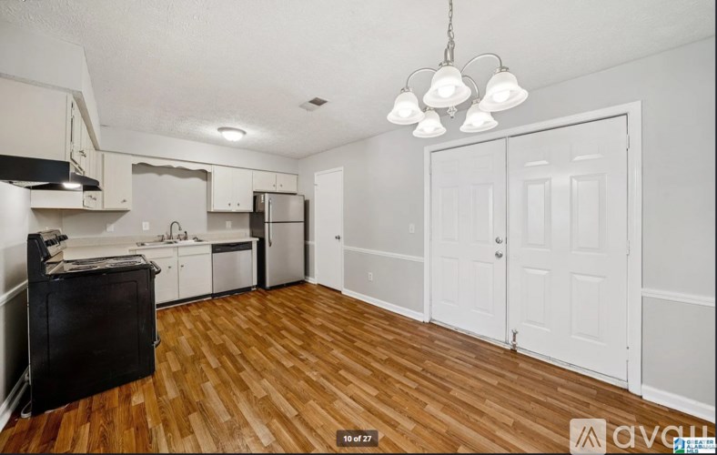 A kitchen with white cabinets and a black refrigerator.