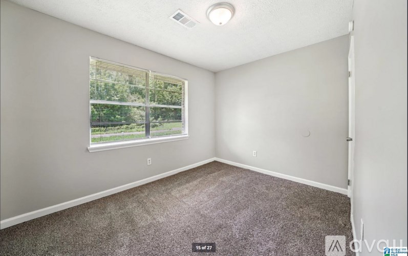 A room with a window and carpeted floor.