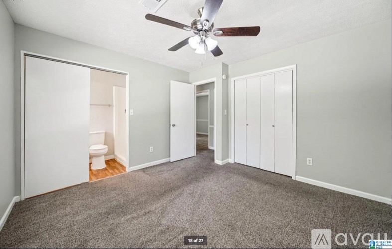 A spacious room with a ceiling fan and carpeted floor.