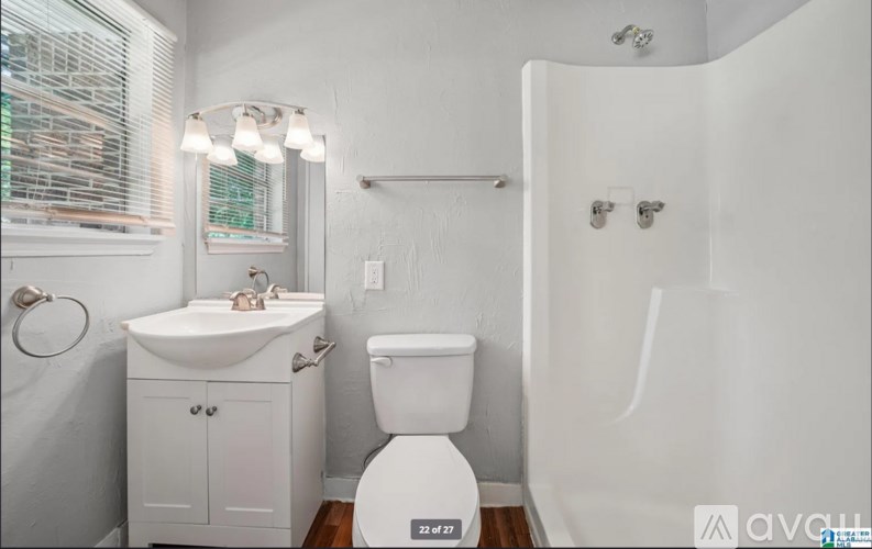A white bathroom with a toilet, sink, and shower.