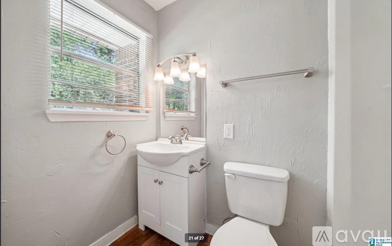 A white bathroom with a toilet, sink, and window.