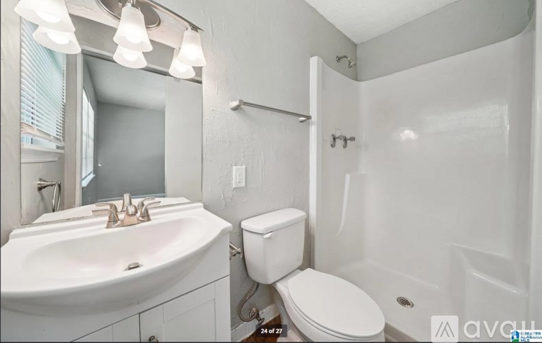 A white bathroom with a toilet, sink, and shower.