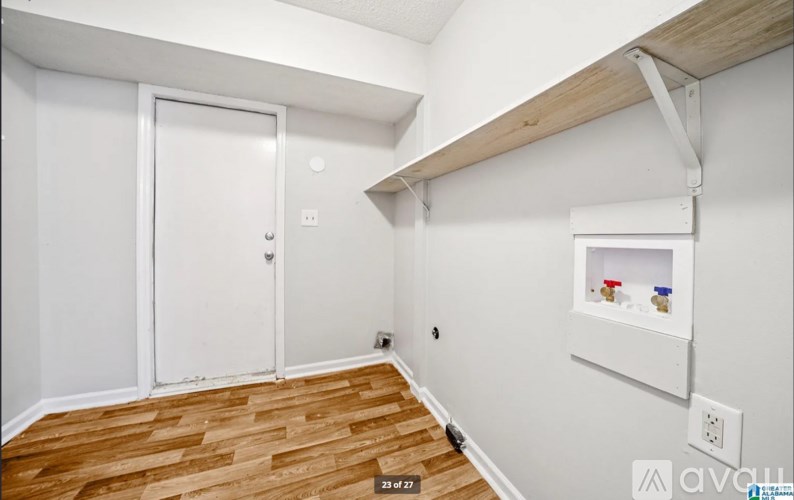 A room with a white door and a shelf with containers on it.