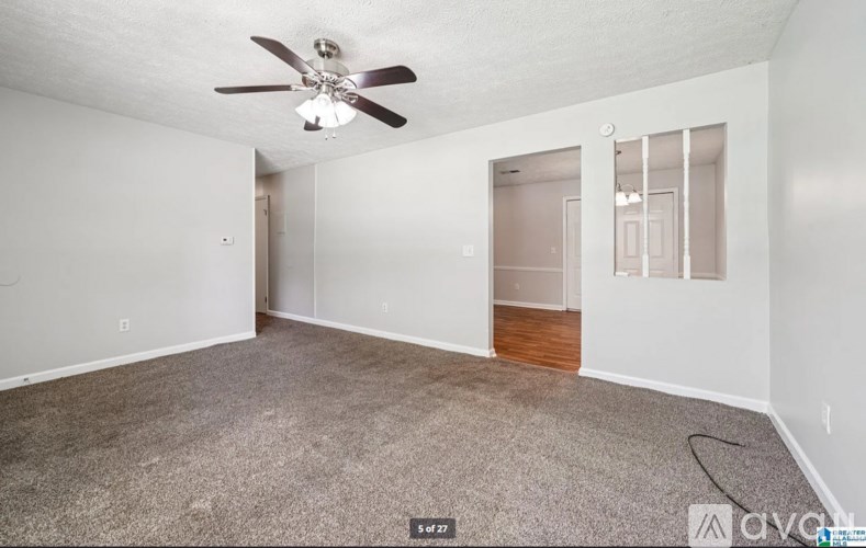 A room with a ceiling fan and carpeted floor.