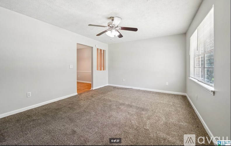 A room with a ceiling fan and carpeted floor.