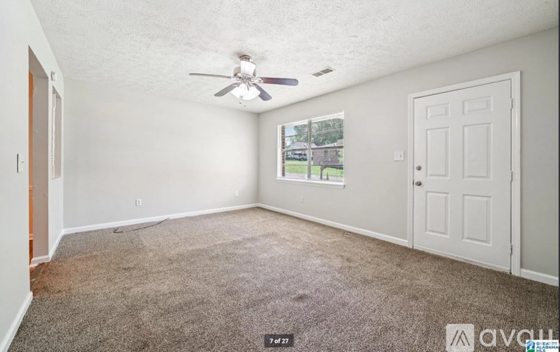 A room with a ceiling fan and carpeted floor.