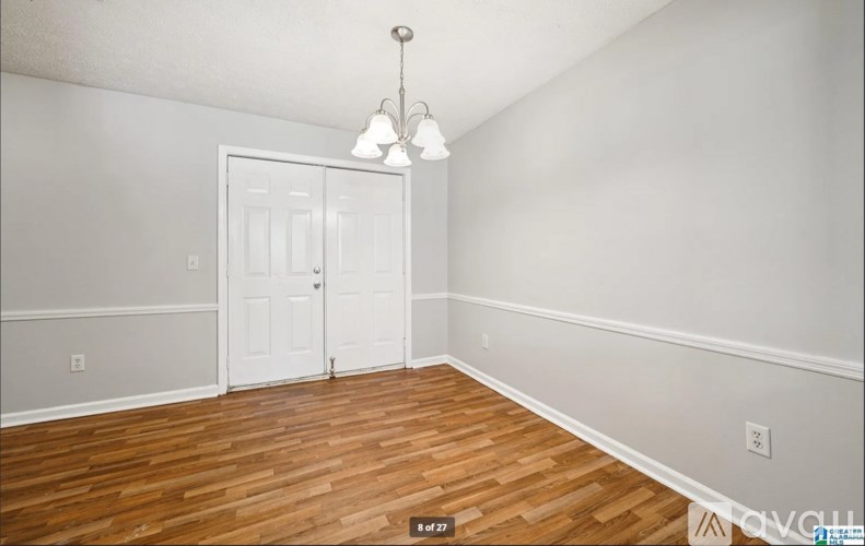A room with a white door and a wooden floor.