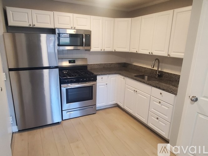 A kitchen with white cabinets and a stainless steel refrigerator.