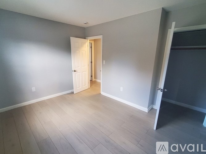 A room with a white door and wooden flooring.