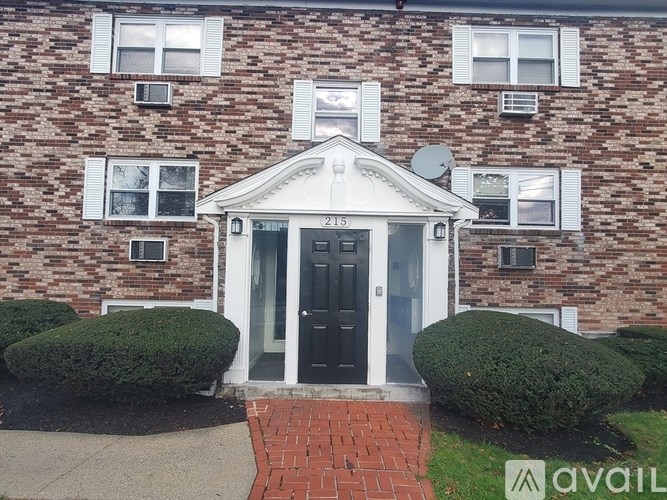 A brick building with a black door and windows with shutters.