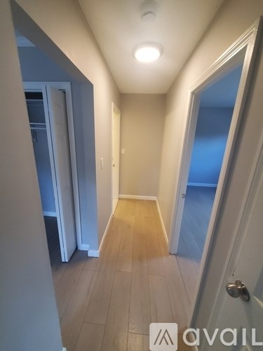 A hallway with a door on the right and a refrigerator in the background.