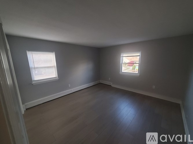 A room with two windows and wooden flooring.