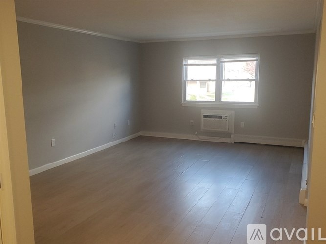 A room with wooden flooring and a window with blinds.
