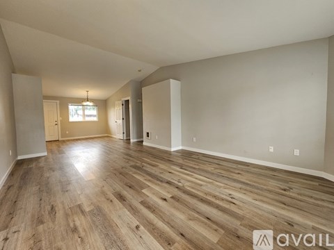 A spacious room with wooden flooring and white walls.
