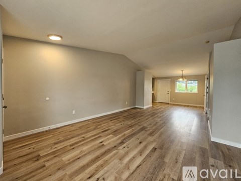 A spacious room with wooden flooring and a door leading to another room.