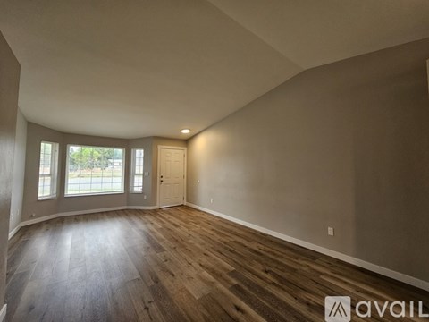 A room with wooden flooring and a door leading to a balcony.